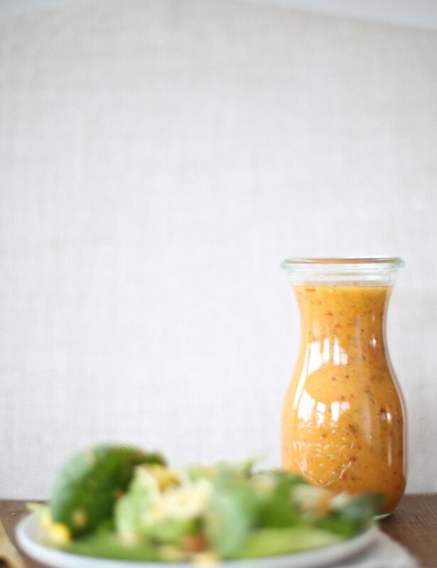 apple chipotle vinaigrette recipe in glass bottle with salad on white plate