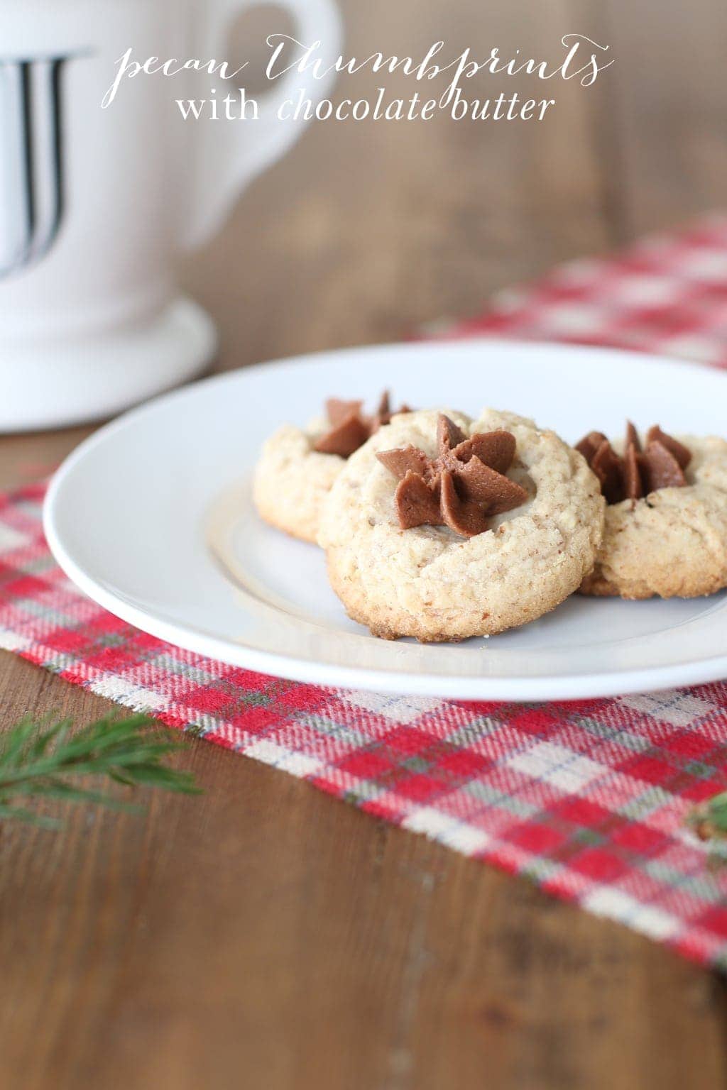 Three pecan thumbprint cookies on a white plate with text overlay