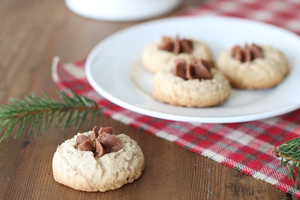 A chocolate iced pecan thumbprint cookie on a table