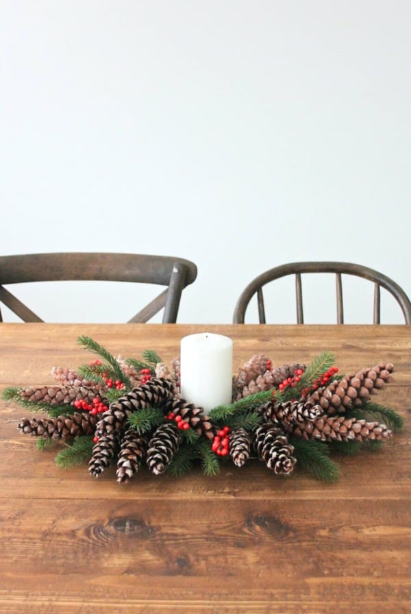 A beautiful Christmas centerpiece adorned with pine cones and berries, displayed on a rustic wooden table.