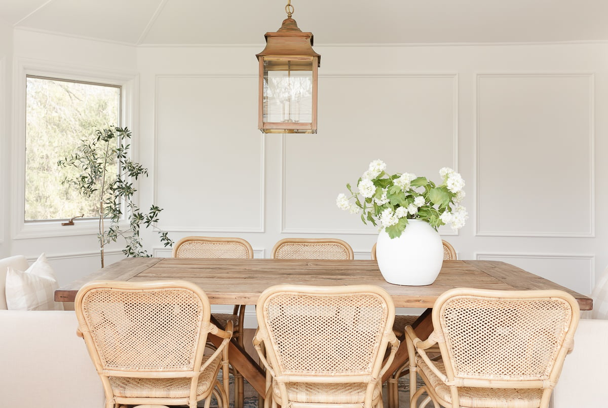 A Restoration Hardware dining table with rattan chairs.