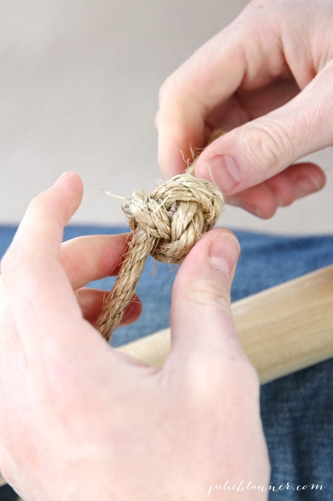 A close up of a hand tying a knot