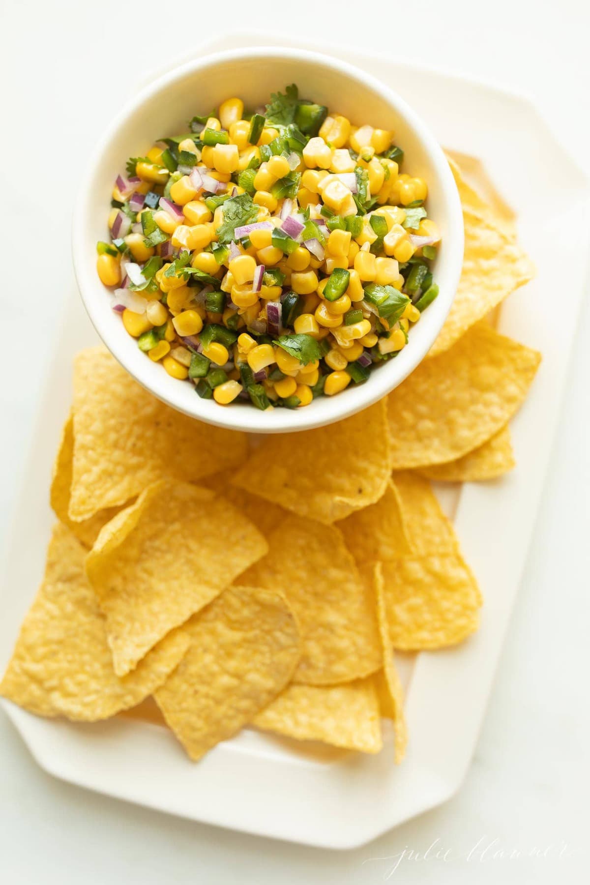 Chipotle corn salsa in a white bowl with chips to the side. 