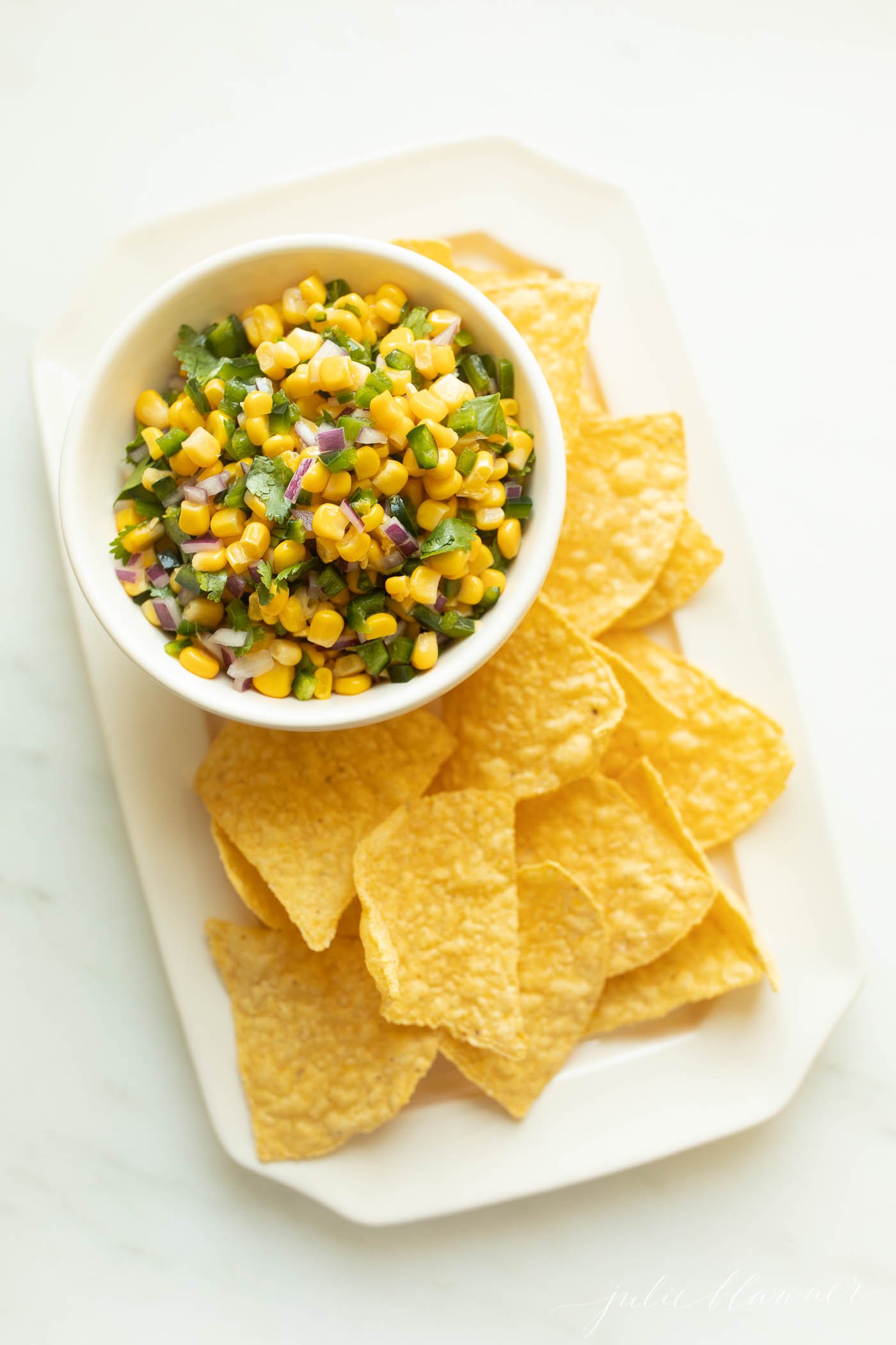 Chipotle corn salsa in a white bowl with chips to the side. 