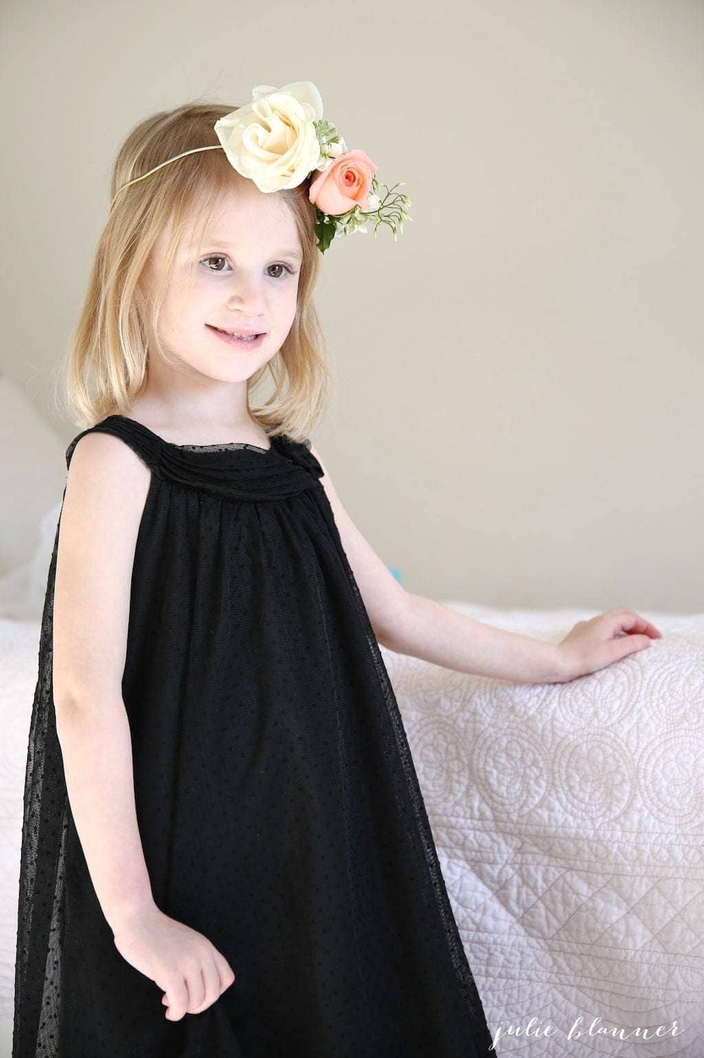 A little girl in a black dress wearing a DIY flower crown.