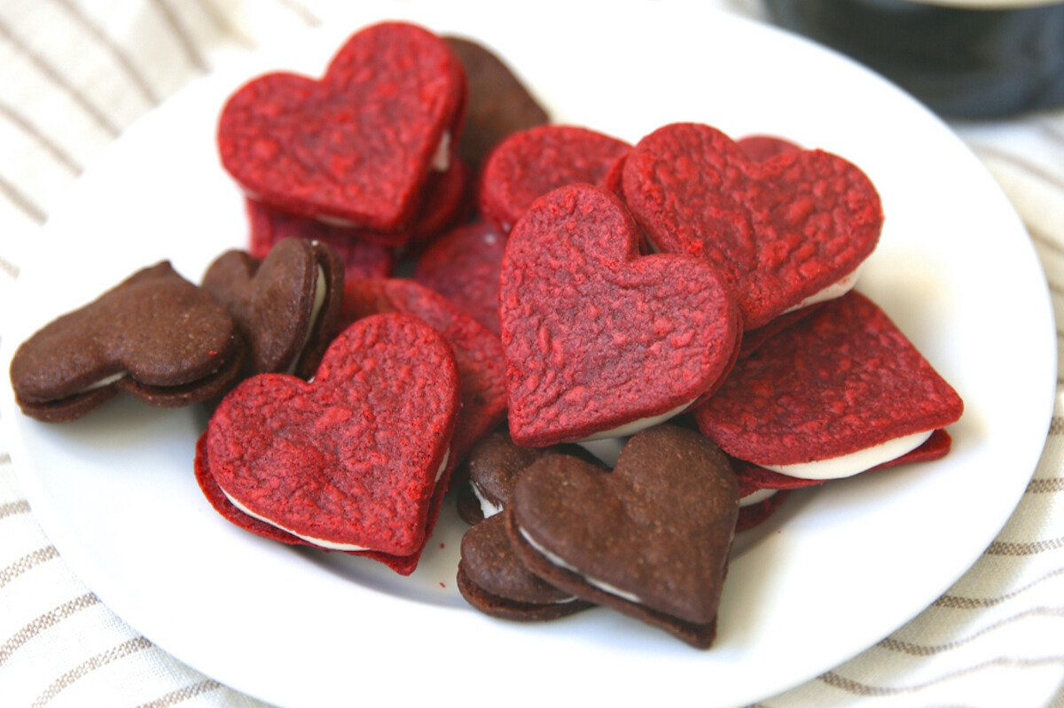 Homemade heart shaped cookies on a plate with a bottle of wine.