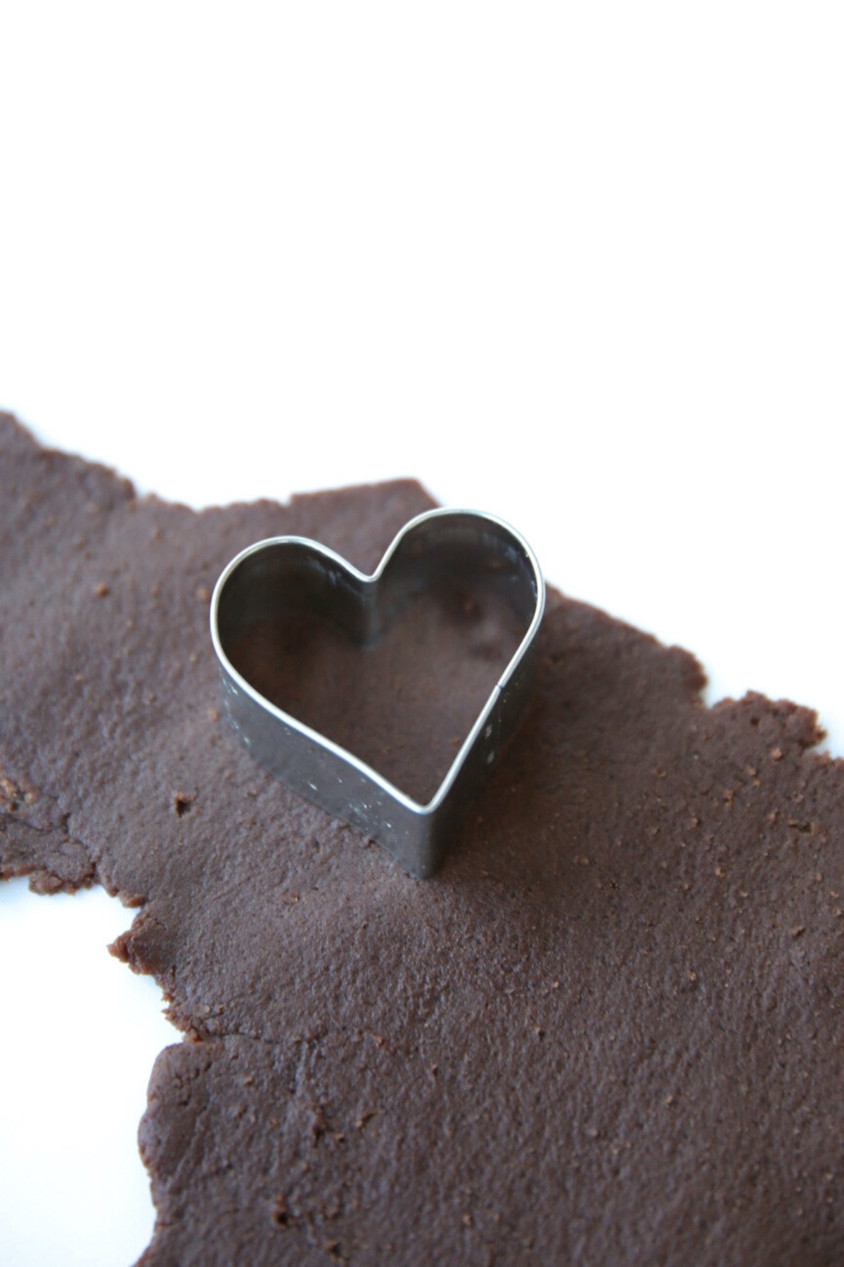 A heart shaped cookie cutter on a piece of chocolate. The chocolaty treat is reminiscent of homemade oreos.