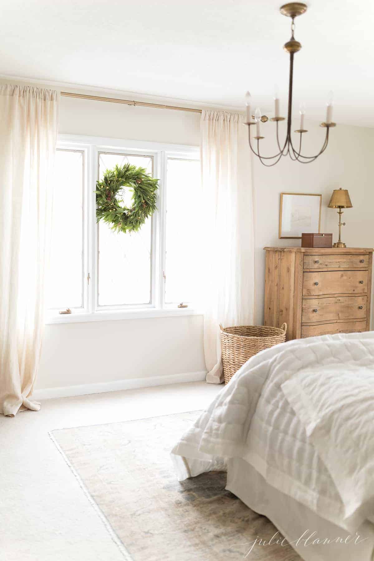 A white bedroom featuring brass lighting with a chandelier and lamp.