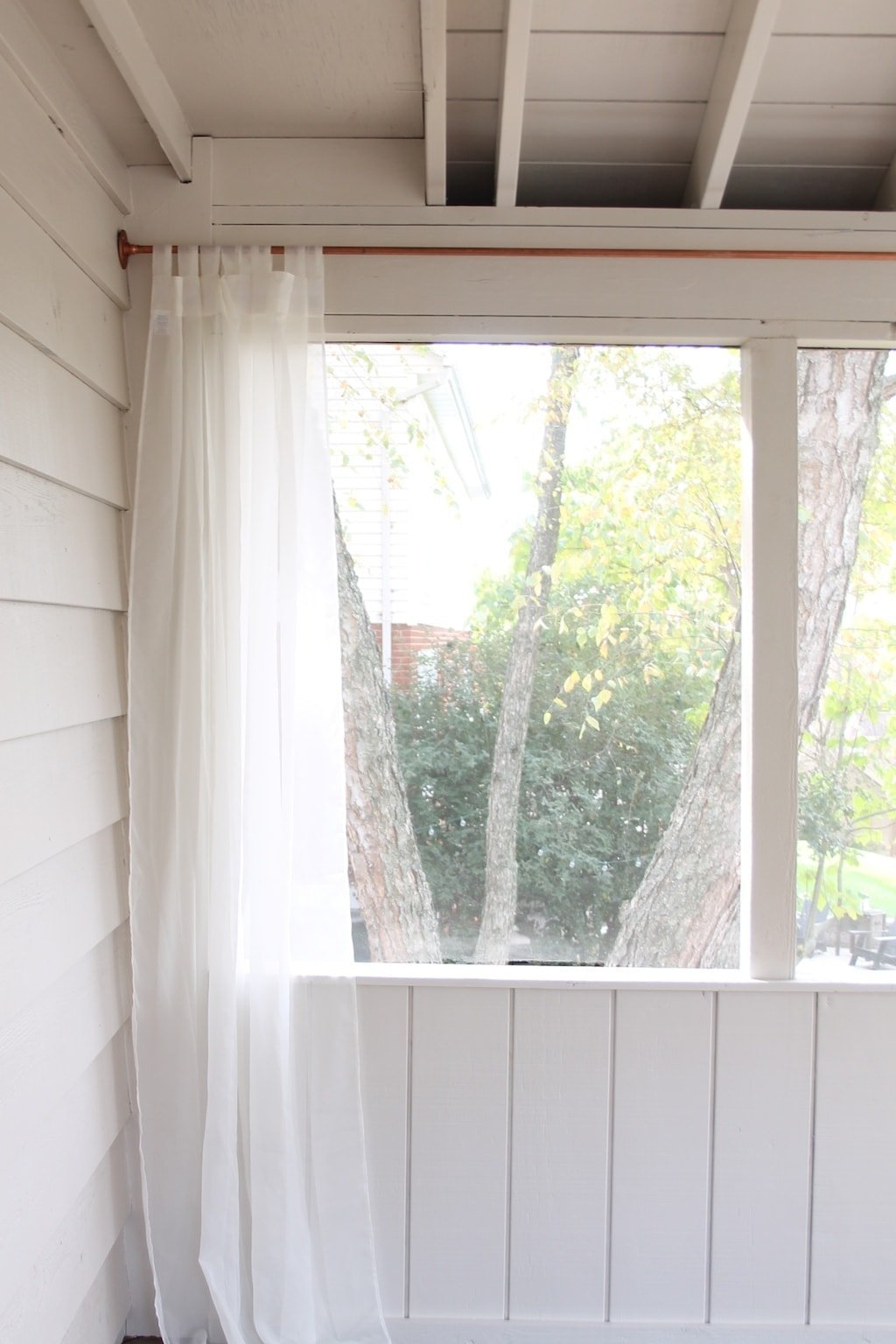 A close up of a window with cream curtains.