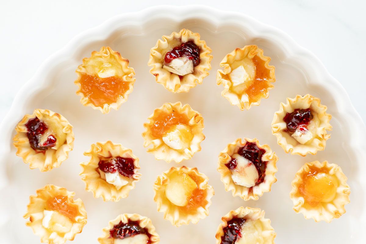 Brie bites topped with jam on a white platter