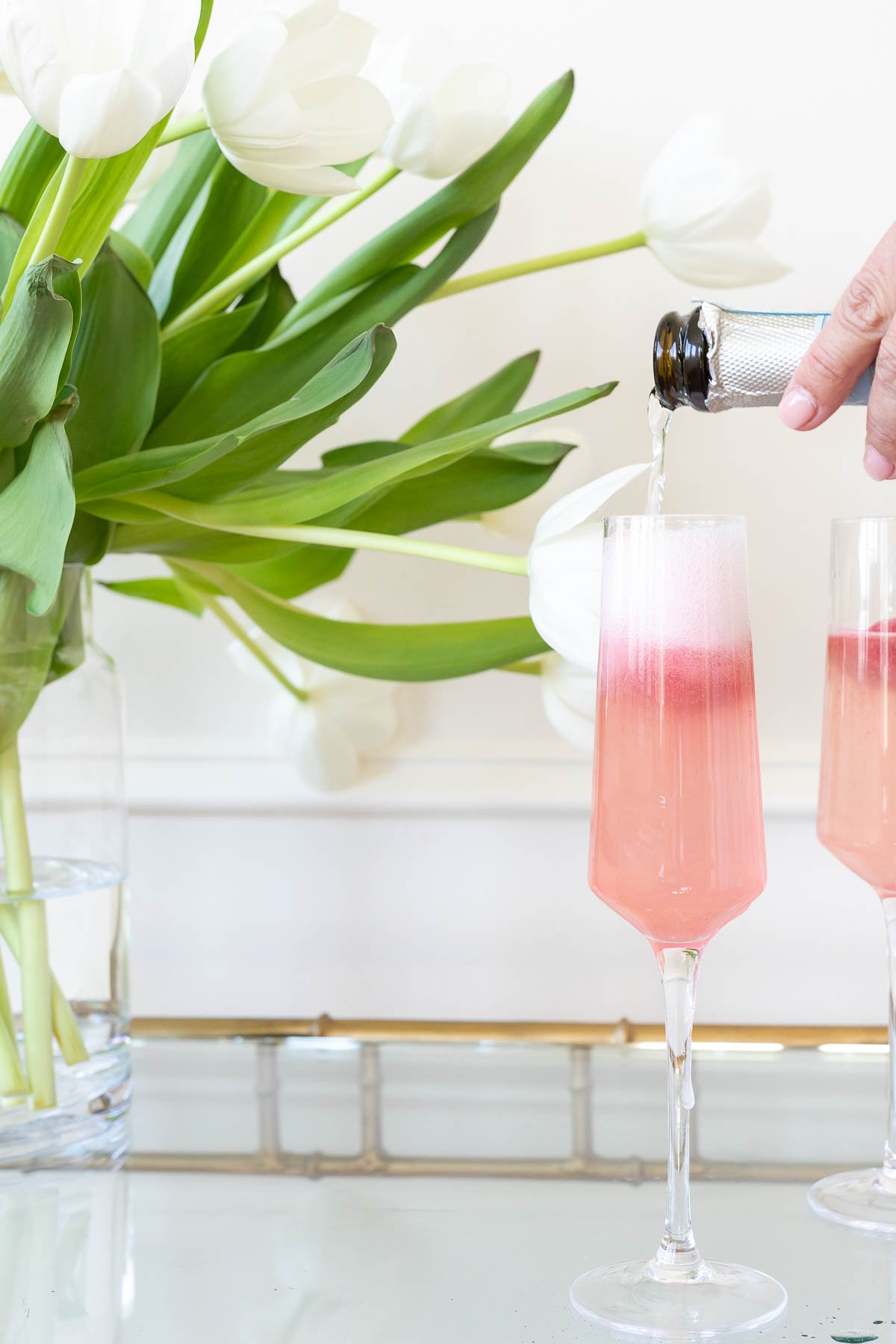white tulips and pink mimosas on a gold bar cart