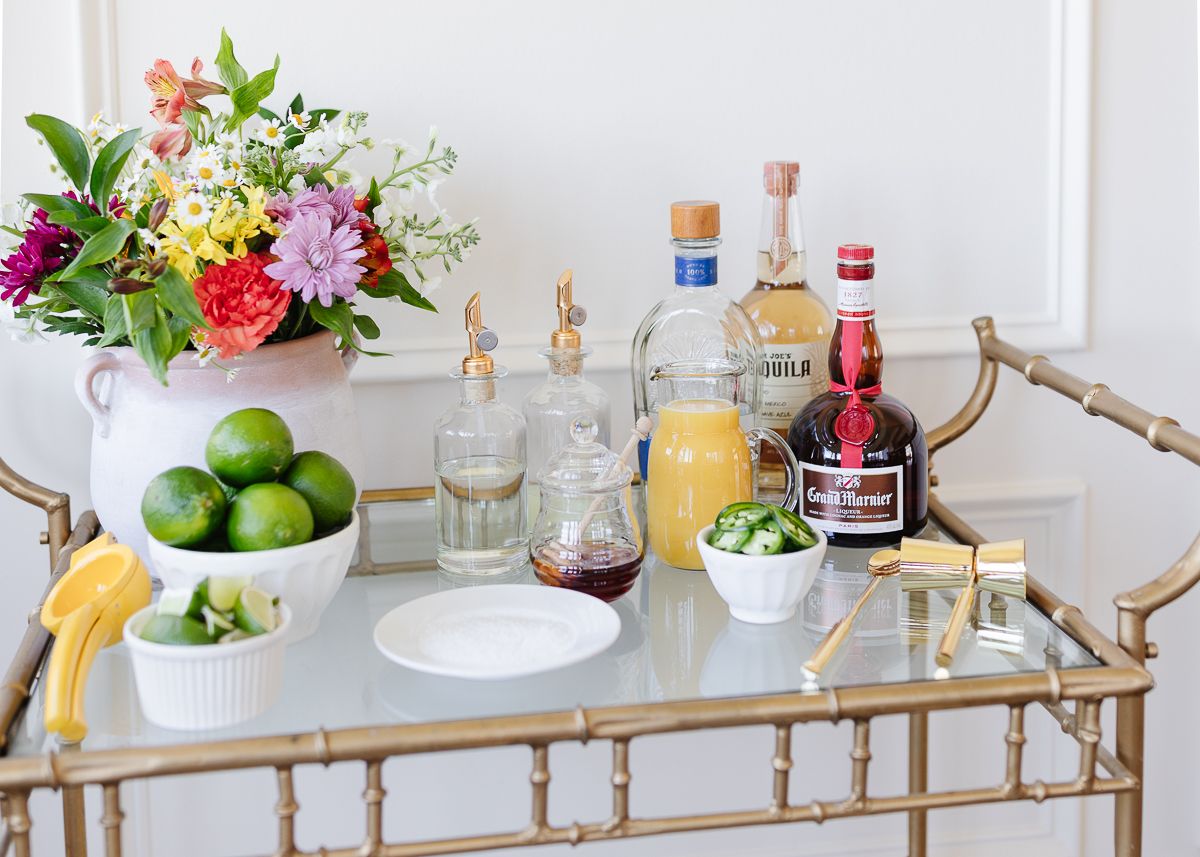 Ingredients for a margarita bar set up on a gold cart