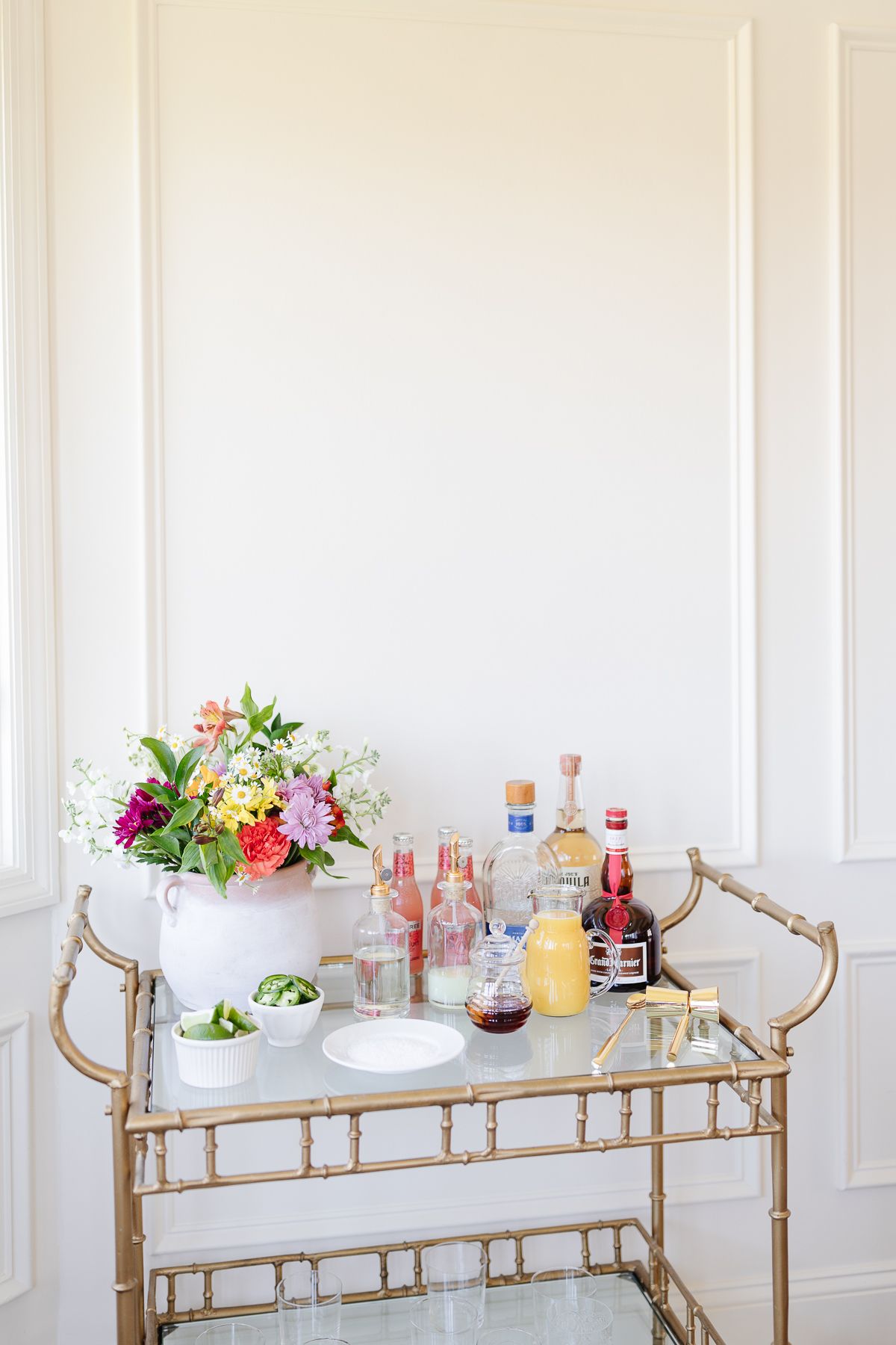 Ingredients for a margarita bar set up on a gold cart