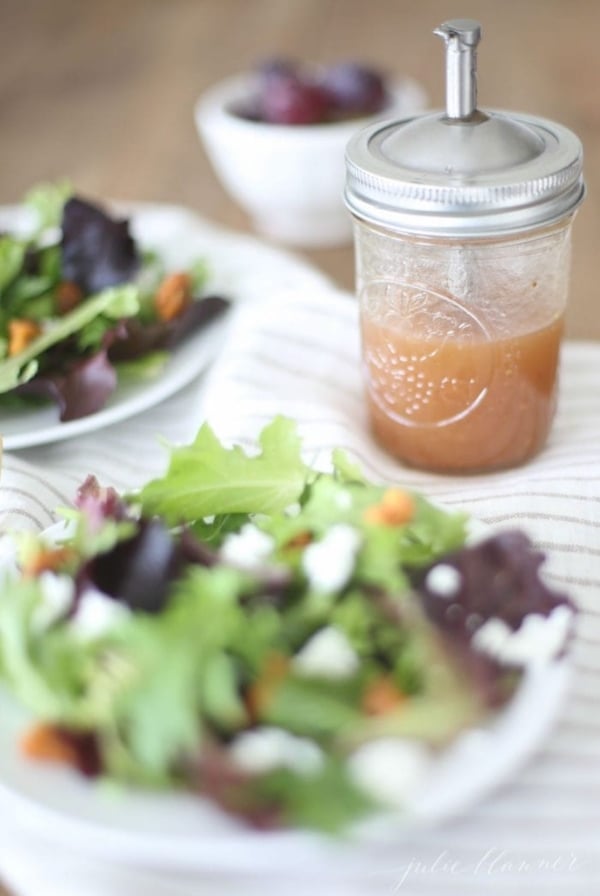 A salad with raspberry vinaigrette dressing on a plate next to a jar.