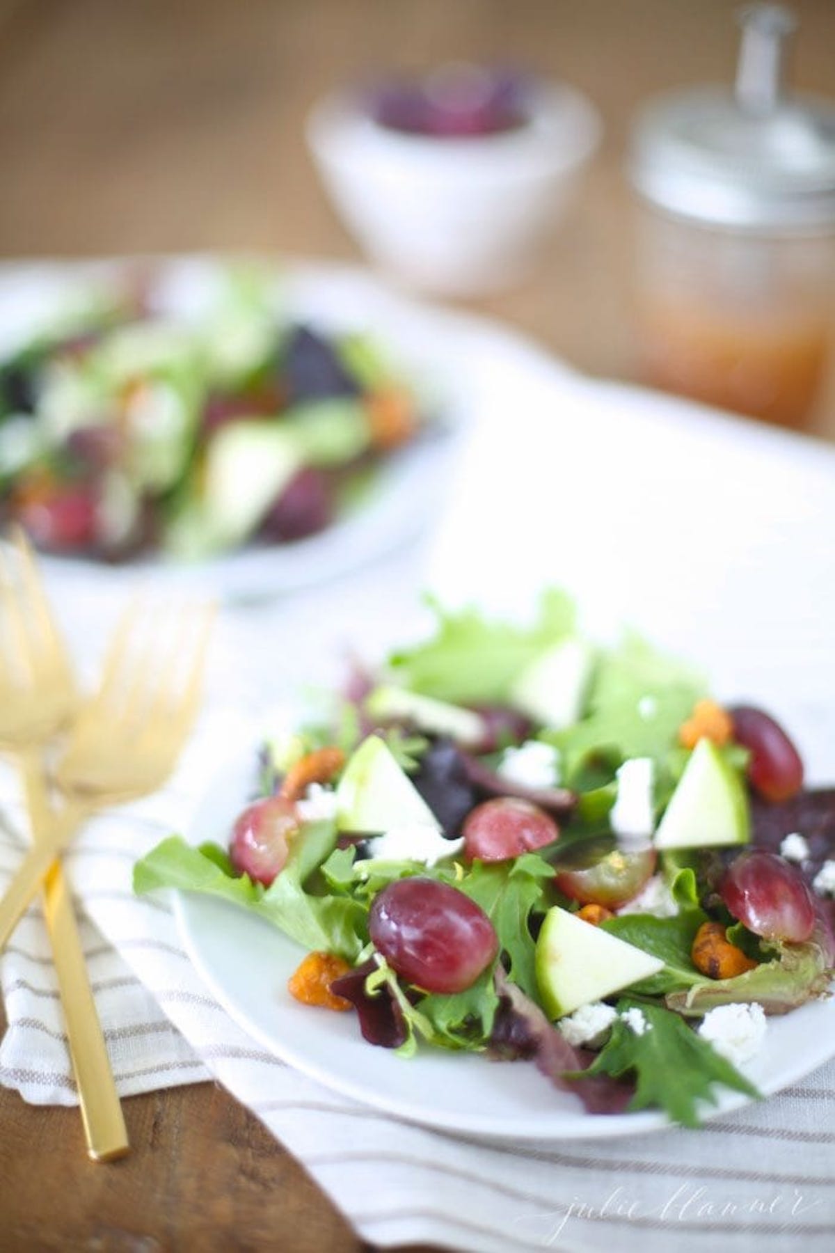 A salad with grapes, walnuts, and raspberry vinaigrette on a plate.