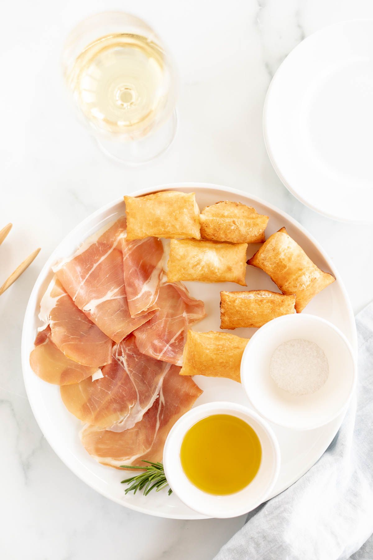 Gnocco fritto on a white plate with bowls of olive oil and sea salt to the side