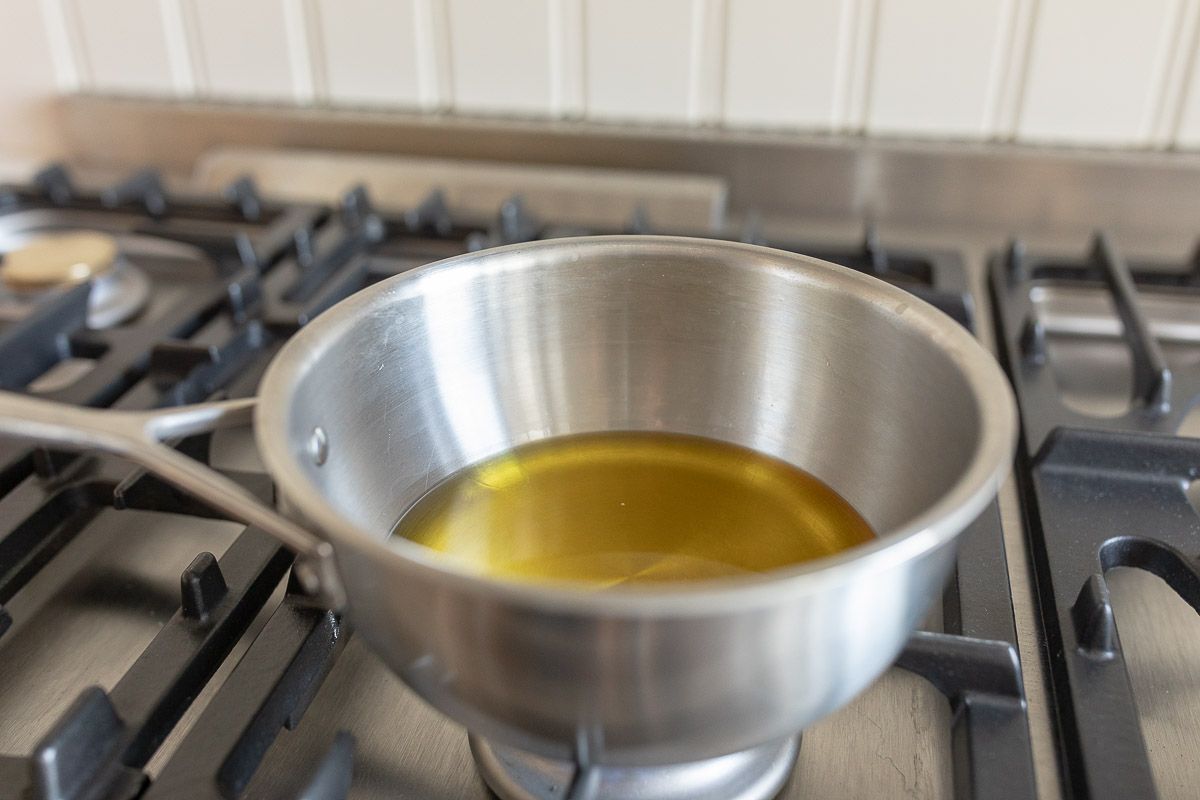 A silver pan on a gas cooktop filled with oil