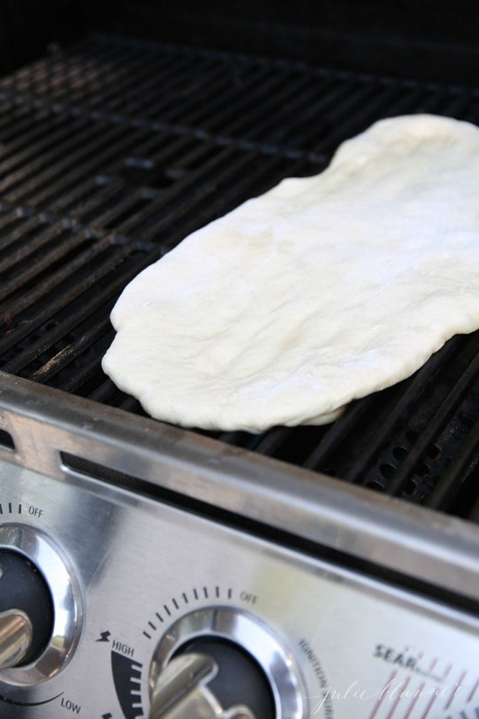 Pizza dough spread out on an outdoor grill