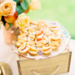 peach crostini place on a plate on top of a wooden crate in an outdoor appetizer display.