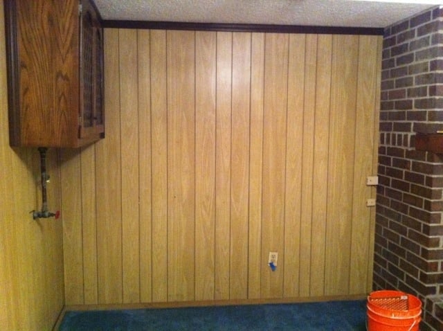 transitioning a basement from dark A dark and dated basement with old paneling and blue carpet.