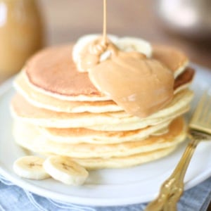A stack of classic pancakes with peanut butter drizzled over them.