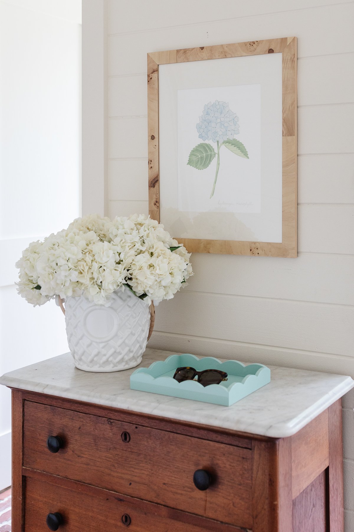 A mudroom with an antique chest and hydrangeas in a vase