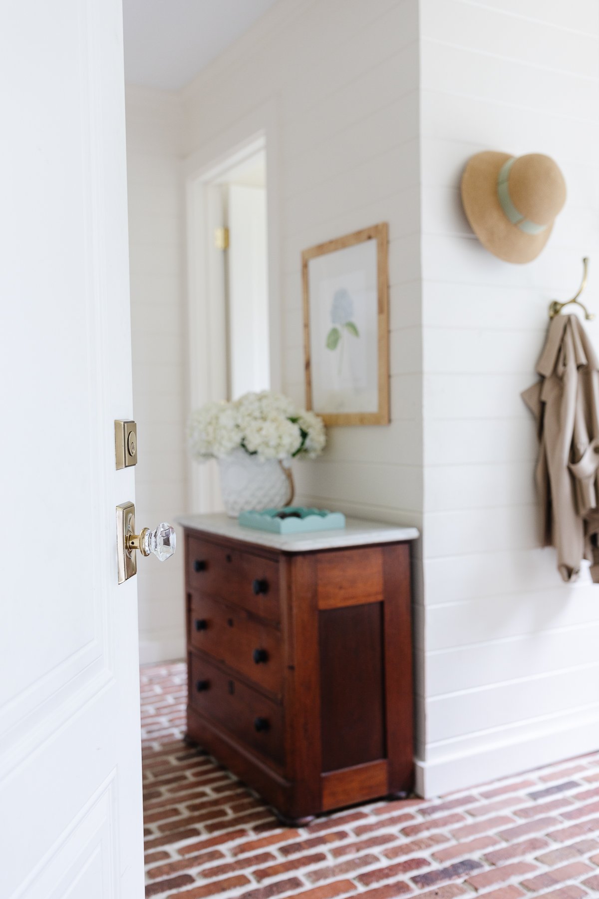 A mudroom with an antique chest and hydrangeas in a vase