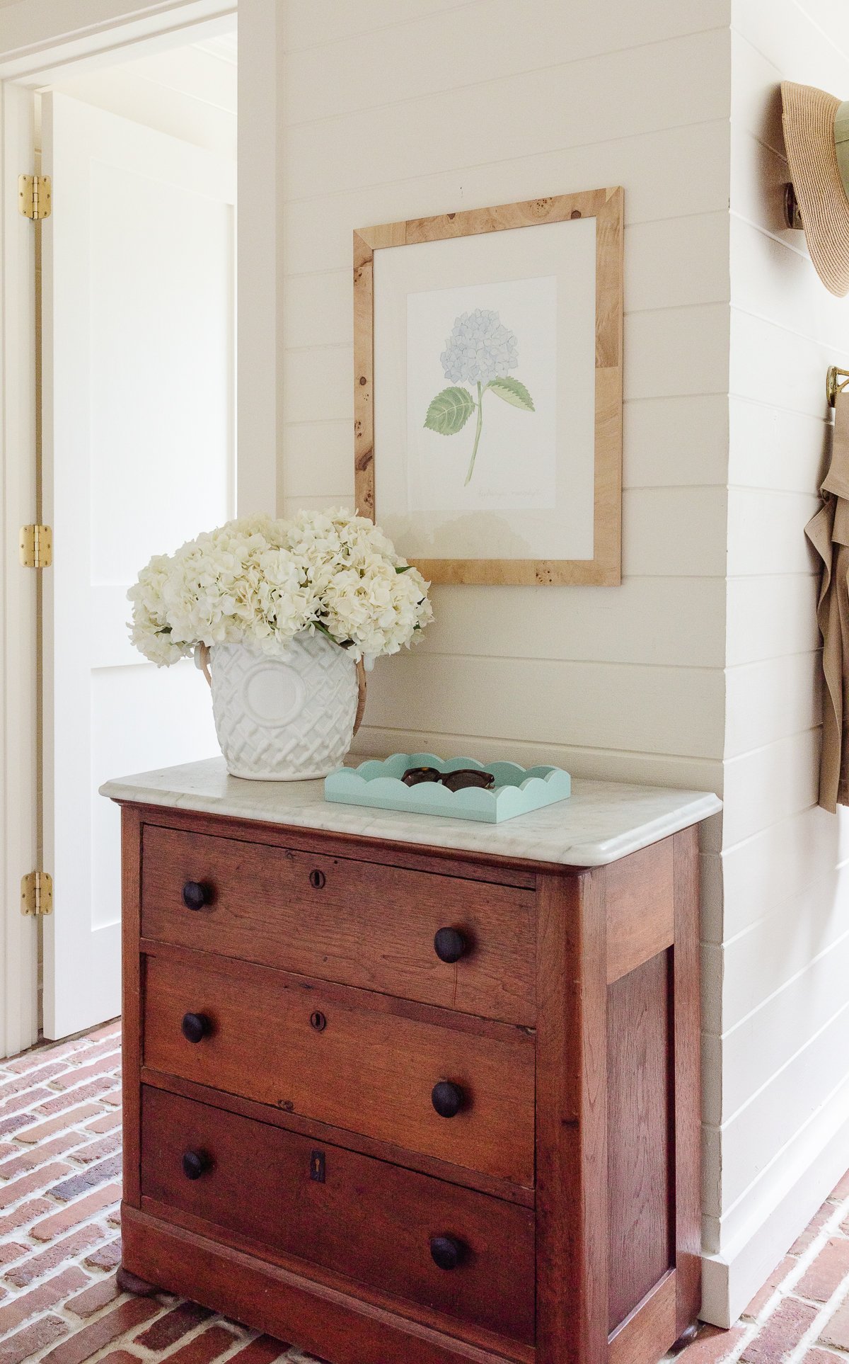 A mudroom with an antique chest and hydrangeas in a vase