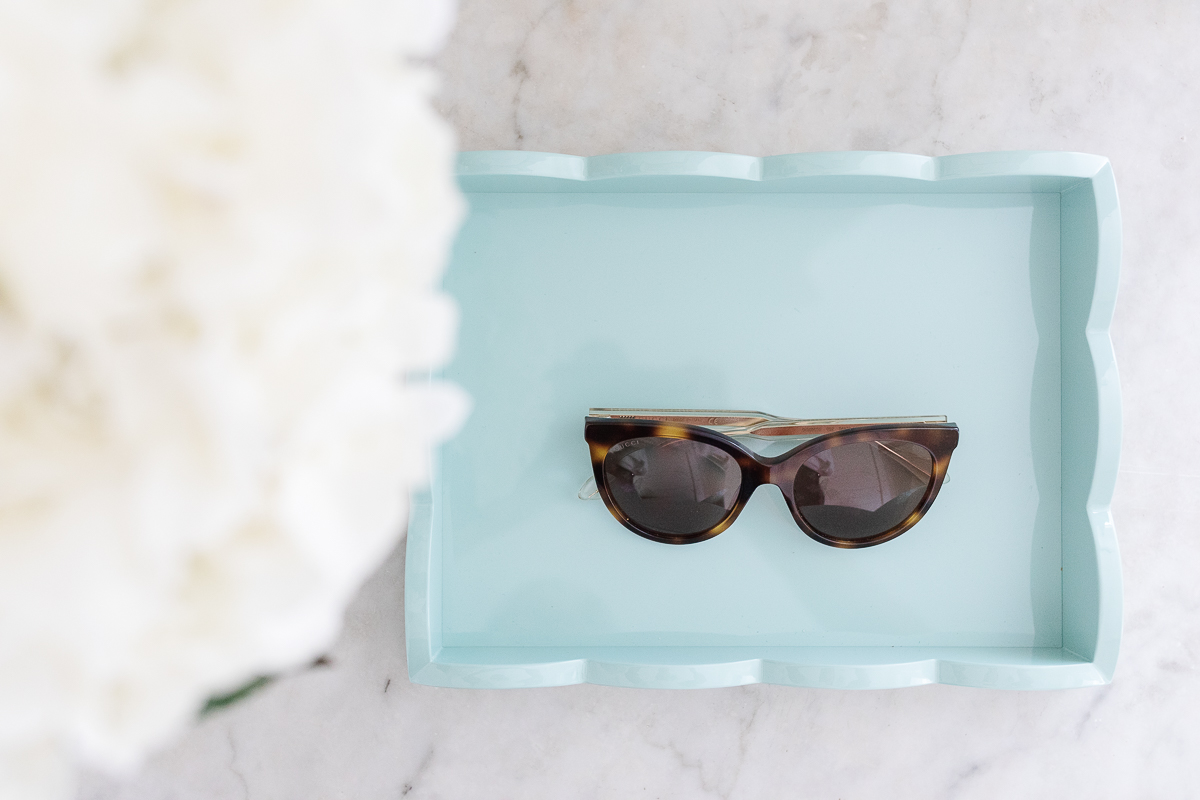 A blue scalloped tray with sunglasses in a mudroom