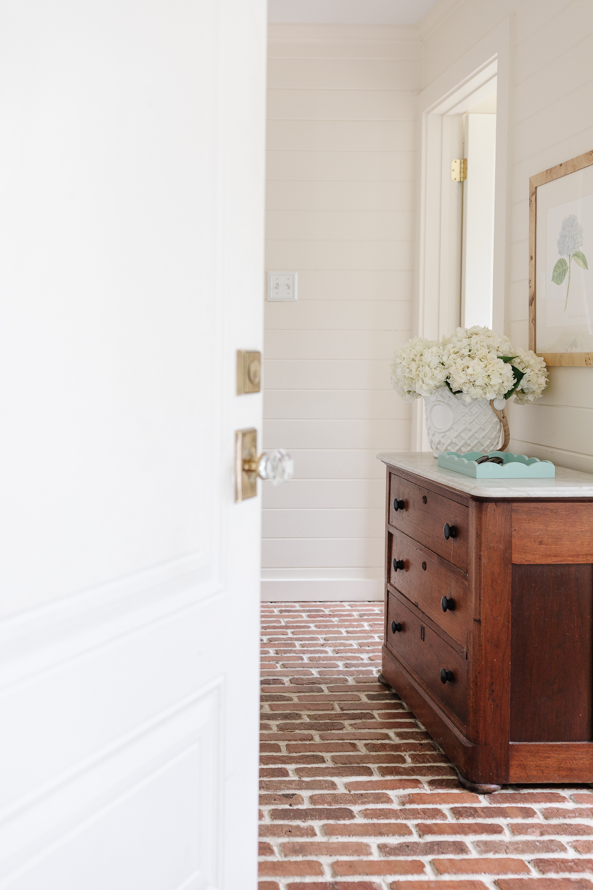 A mudroom with an antique chest and hydrangeas in a vase