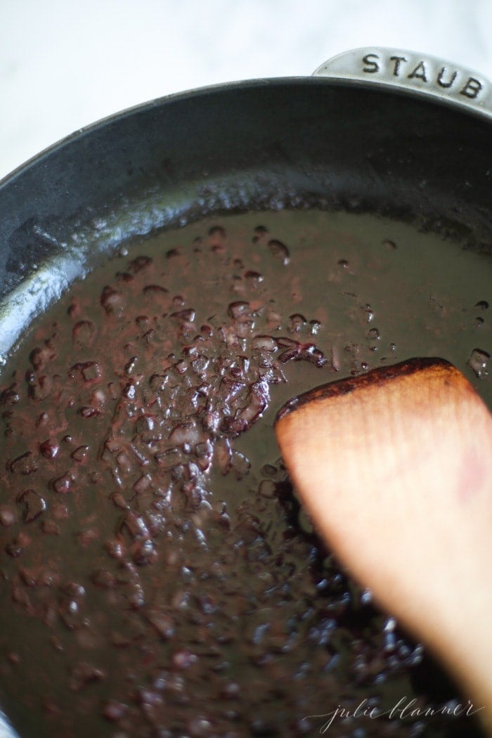 An incredible Red Wine Sauce for Steak that can be made in less than 20 minutes! Whether you call it red wine jus or gravy, its such an elegant meal! red wine sauce cooking in skillet with wooden spoon