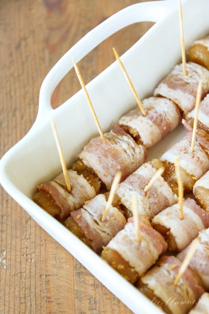Bacon wrapped chicken bites in a casserole dish before being cooked