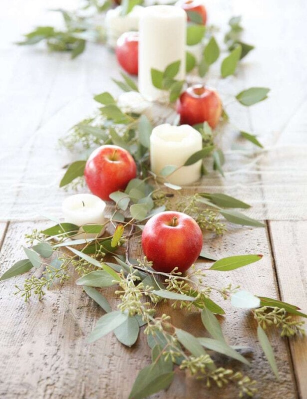 apple centerpiece on wood table with candles apples and eucalyptus