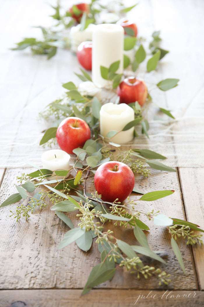 apple centerpiece on wood table with candles apples and eucalyptus