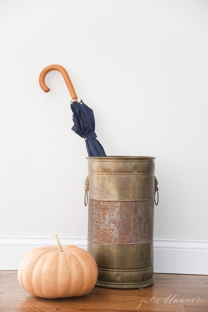 A copper bucket used as an umbrella stand.