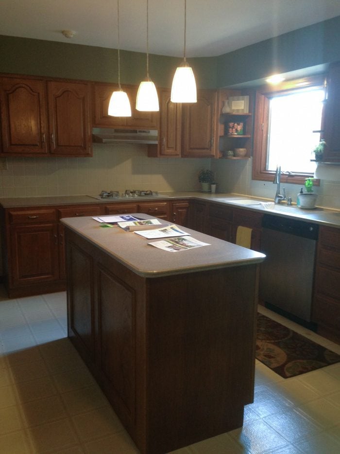 kitchen "before" image featuring dated oak kitchen cabinets and light fixtures