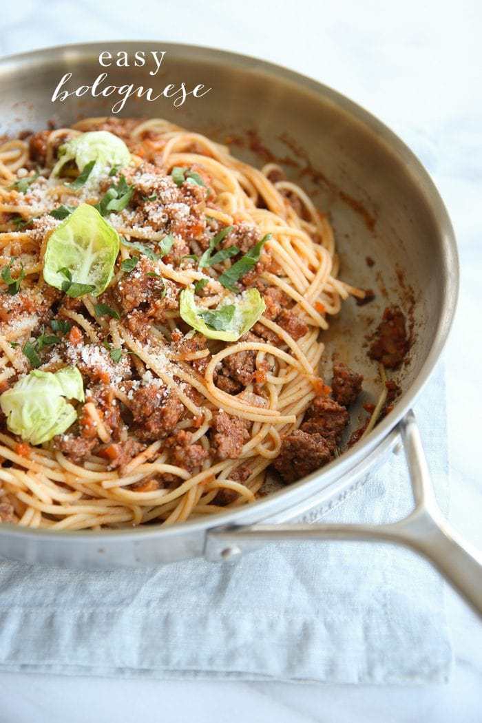 Bolognese pasta in a pan topped with parmesan.