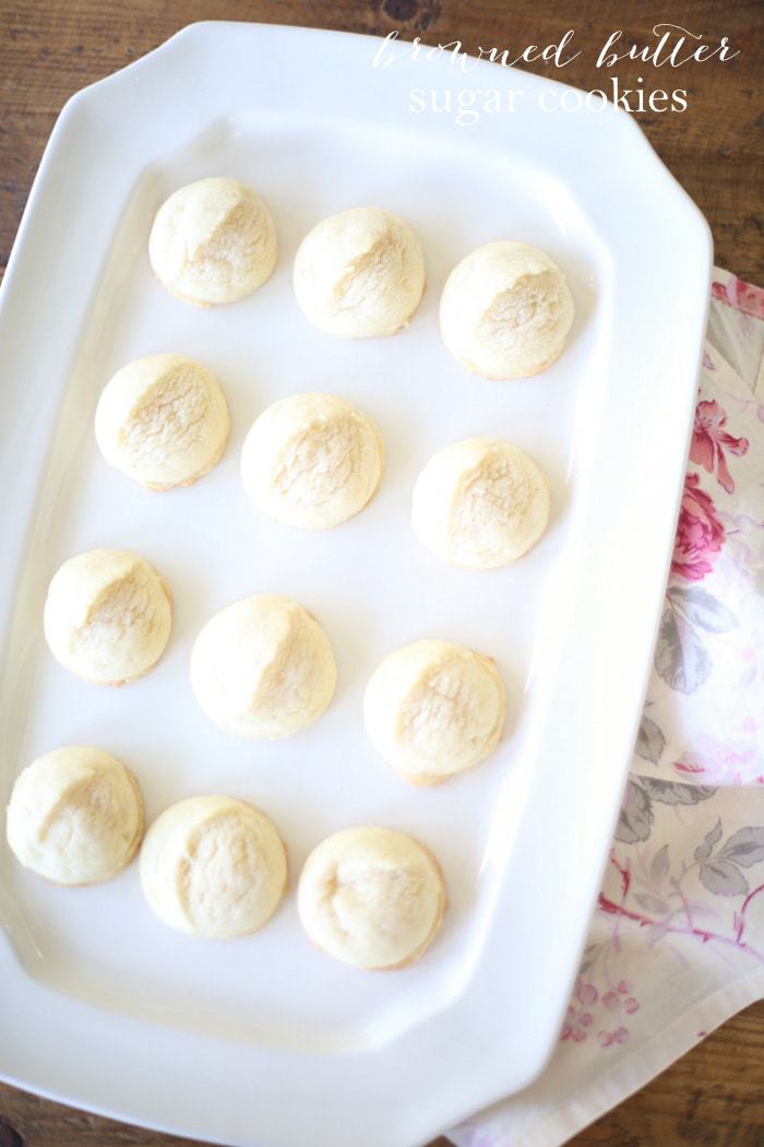 A white platter full of round browned butter sugar cookies.