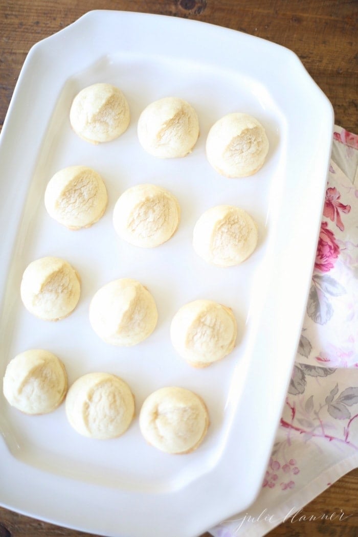 A white platter full of round browned butter sugar cookies.