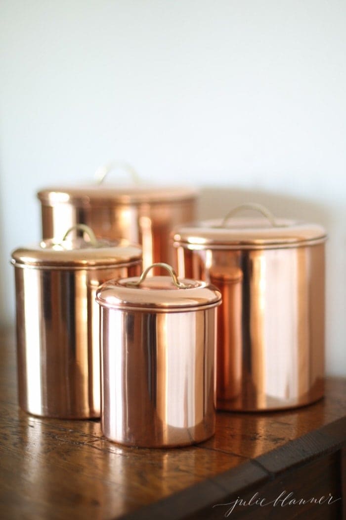 Set of 4 copper kitchen canisters on a wood desk