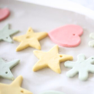 Pastel-colored star and heart-shaped colored salt dough ornaments on parchment paper.