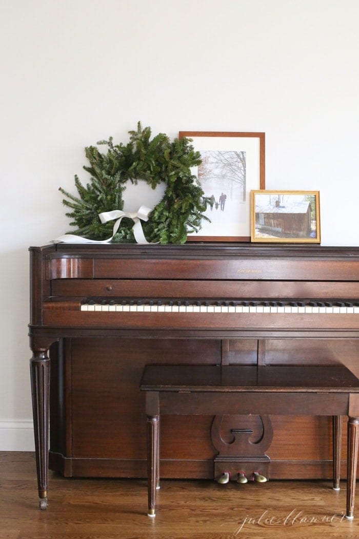 Winter decor of a family photo in the snow, plus an evergreen wreath on a piano.