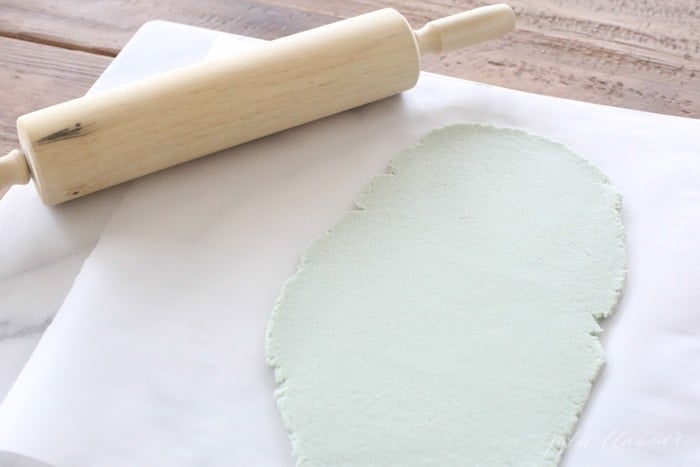 blue salt dough rolled out onto parchment with rolling pin