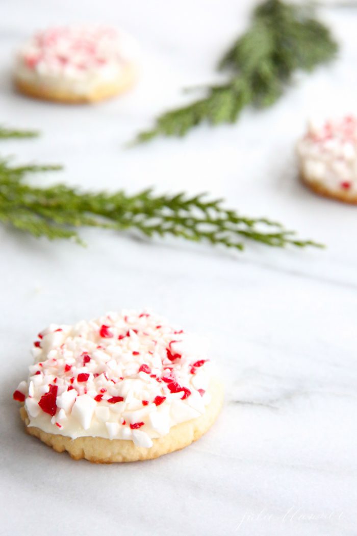 peppermint sugar cookies on marble countertop with holly leaves