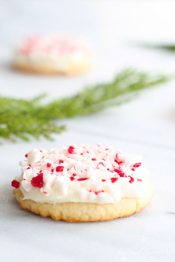 peppermint Christmas cookies on marble countertop with holly leaves