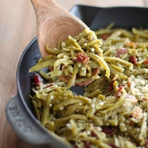 green beans with bacon in cast iron pan with wood spoon