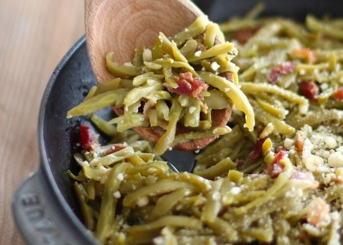 green beans with bacon in cast iron pan with wood spoon