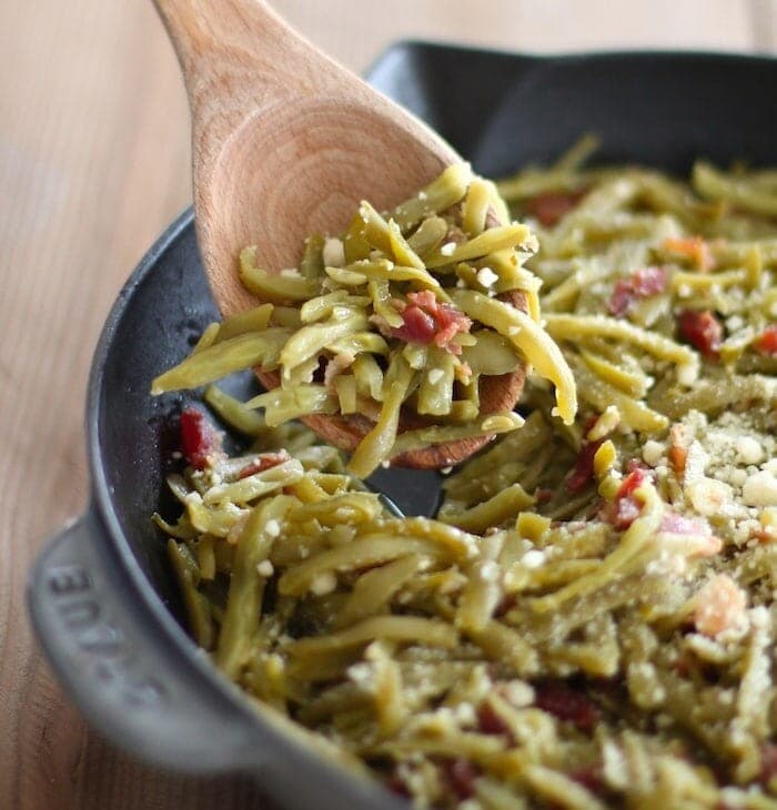 green beans with bacon in cast iron pan with wood spoon