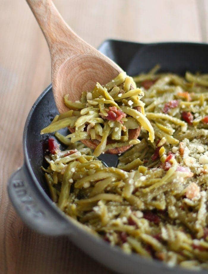 green beans with bacon in cast iron pan with wood spoon