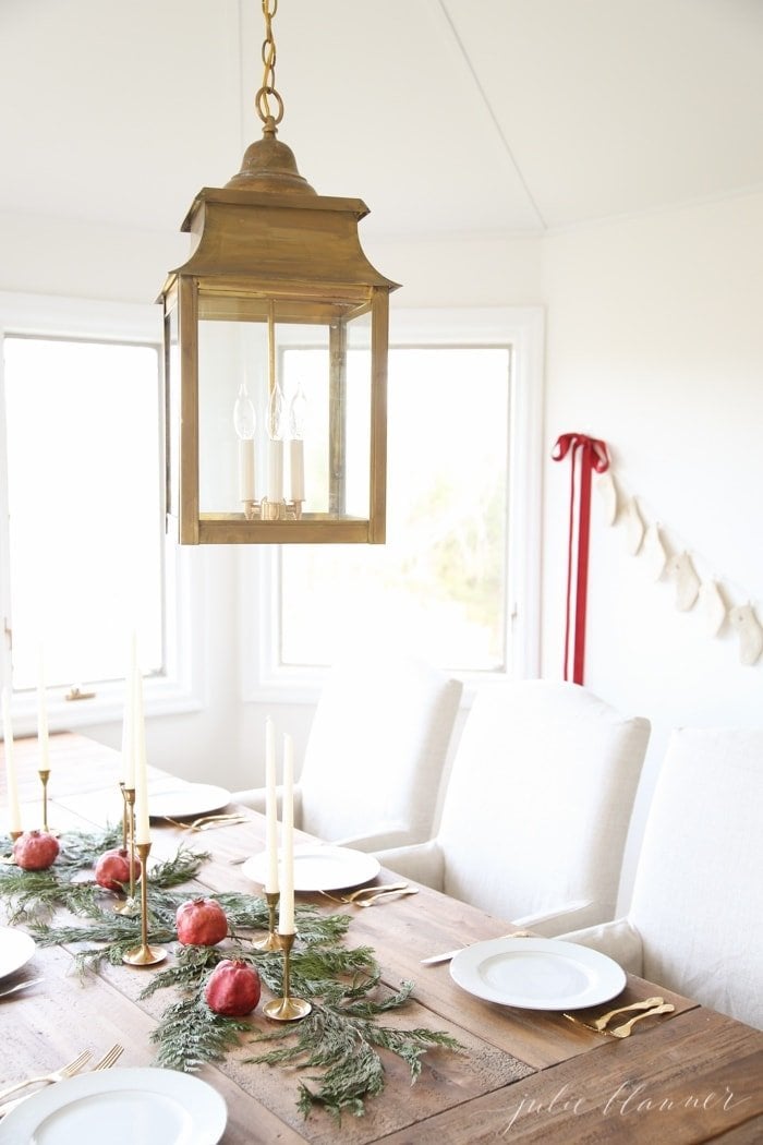 A farm table with white linen chairs and a christmas centerpiece